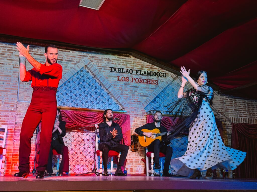 Male and female flamenco dancers with guitar player and two singers behind them on stage at Tablao Flamenco Los Porches in Madrid, Spain