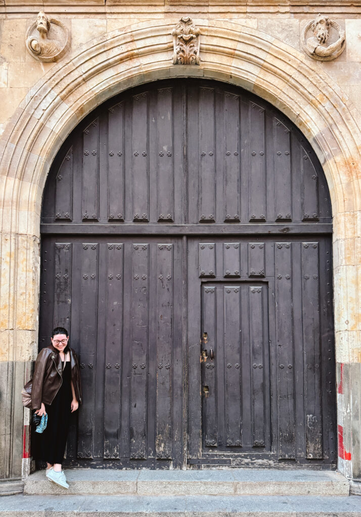 Woman in brown standing in front of a brown door in European small town