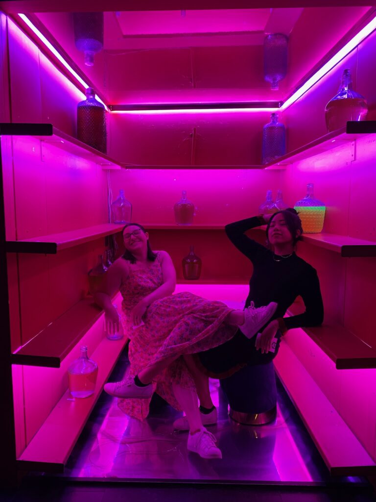 Two women posing in a pink lit up corner of a bar in Madrid nightlife