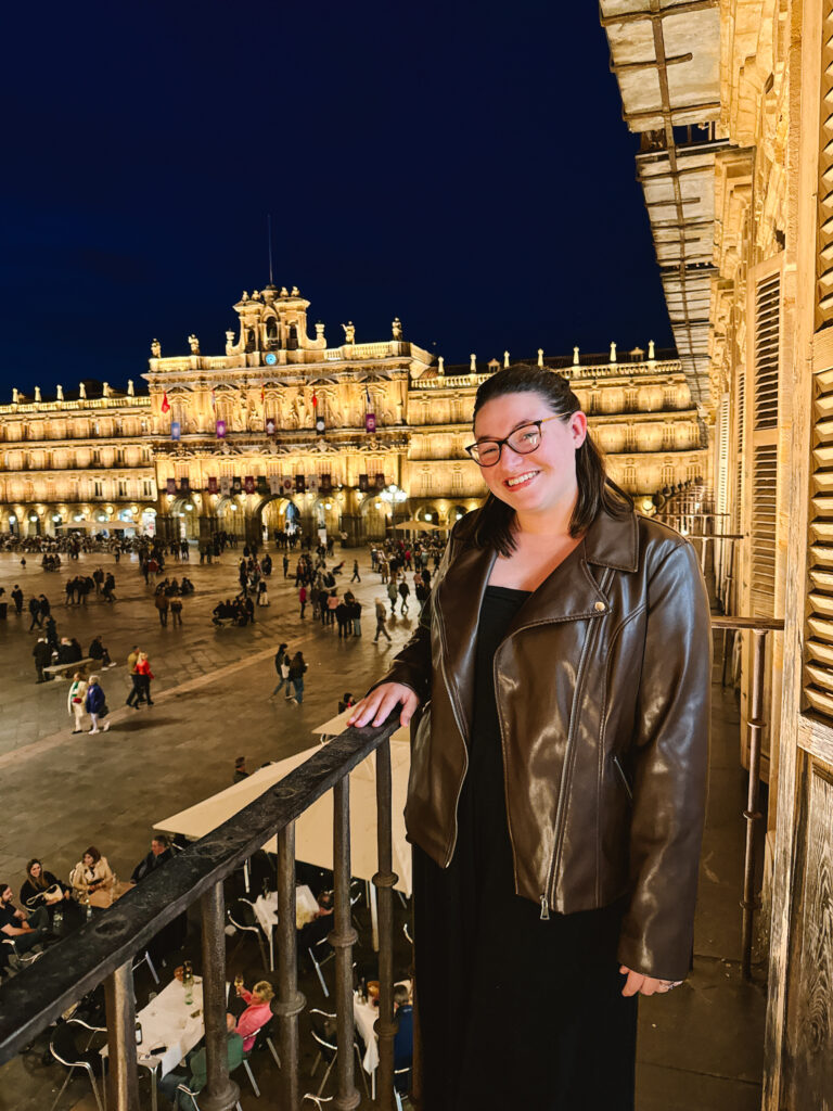Woman standing on a balcony at night in Plaza Mayor in Salamanca, Spain.