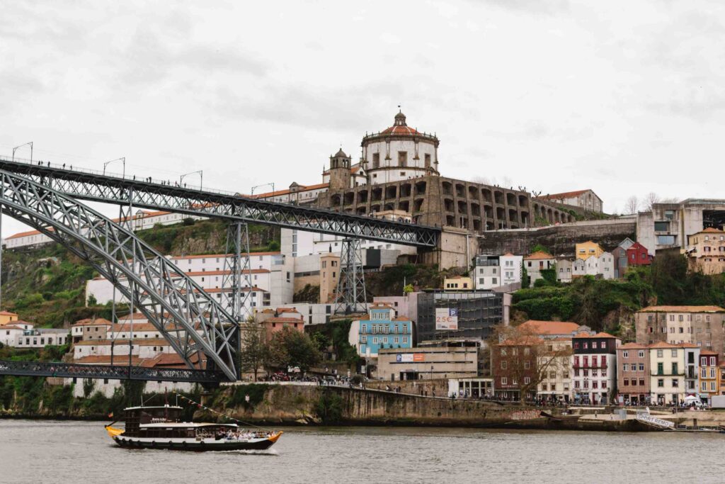 View of Porto waterfront with bridge and boat traveling across the water