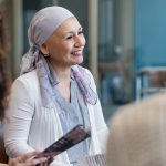 Woman wearing head scarf to cover bald head smiles while talking to providers