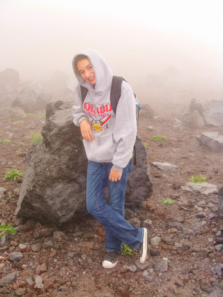 girl leaning on a large volcanic boulder in Mount Fuji Japan