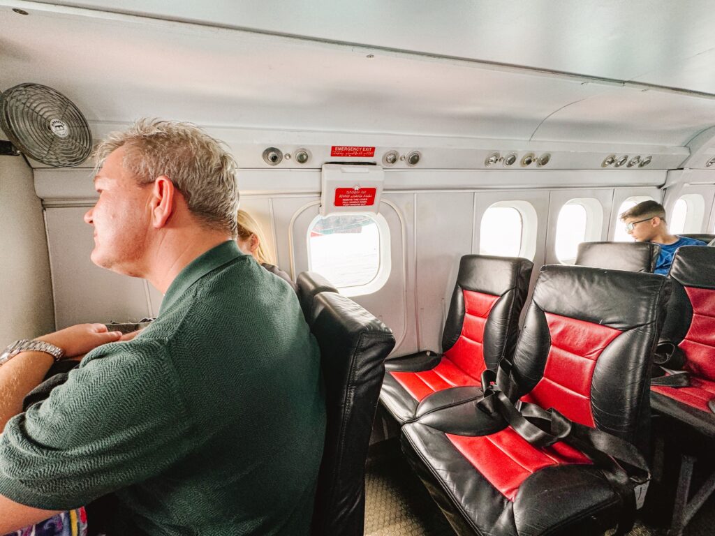 Rows of two seats in a seaplane with a few passengers sitting looking out the windows