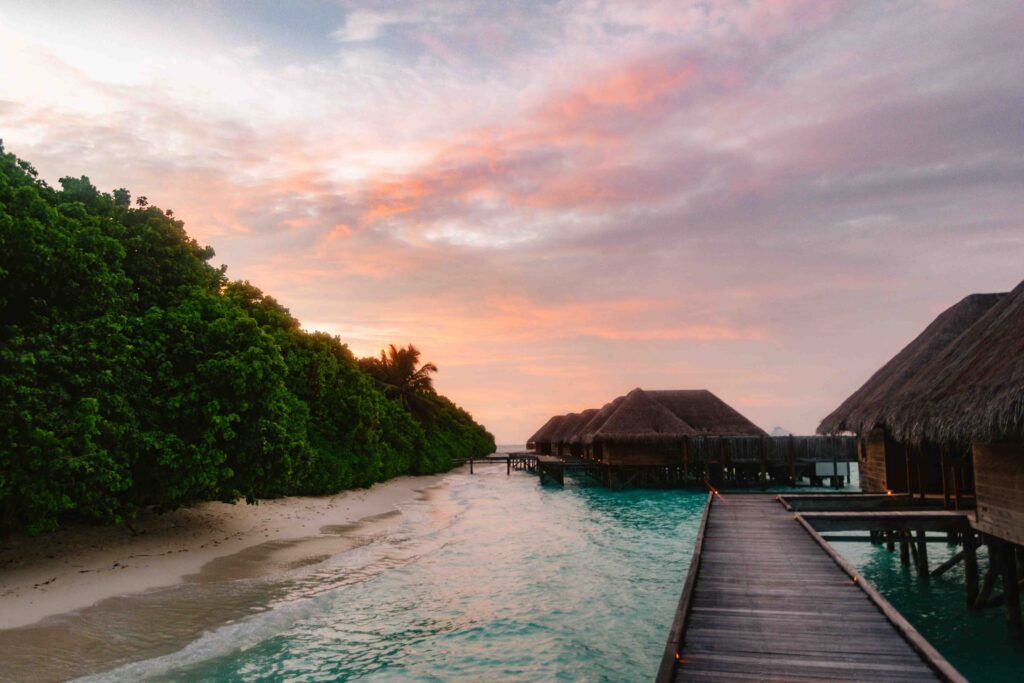 Sunset in the Maldives with overwater villas in the foreground